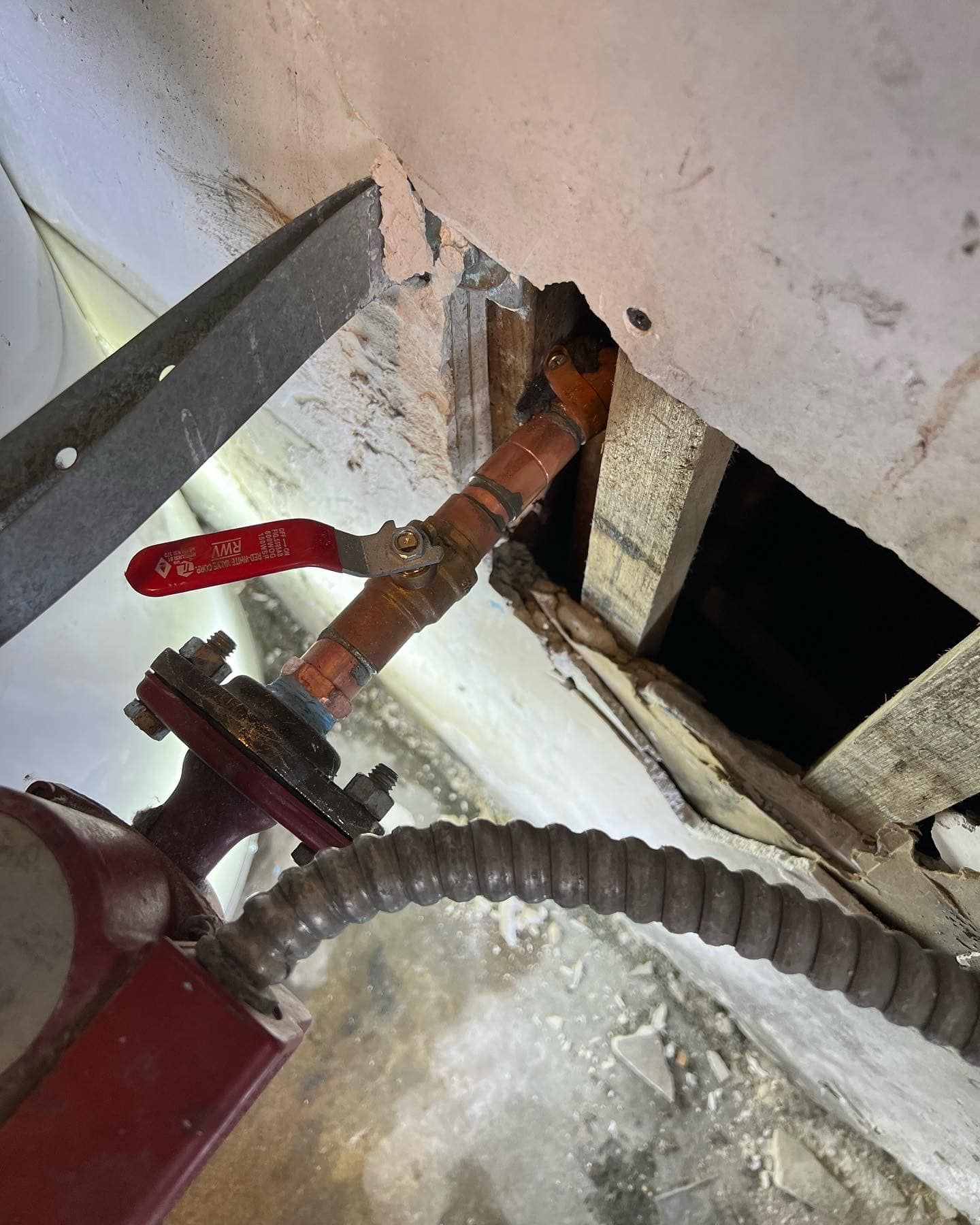 A red valve is connected to a hose in a room.