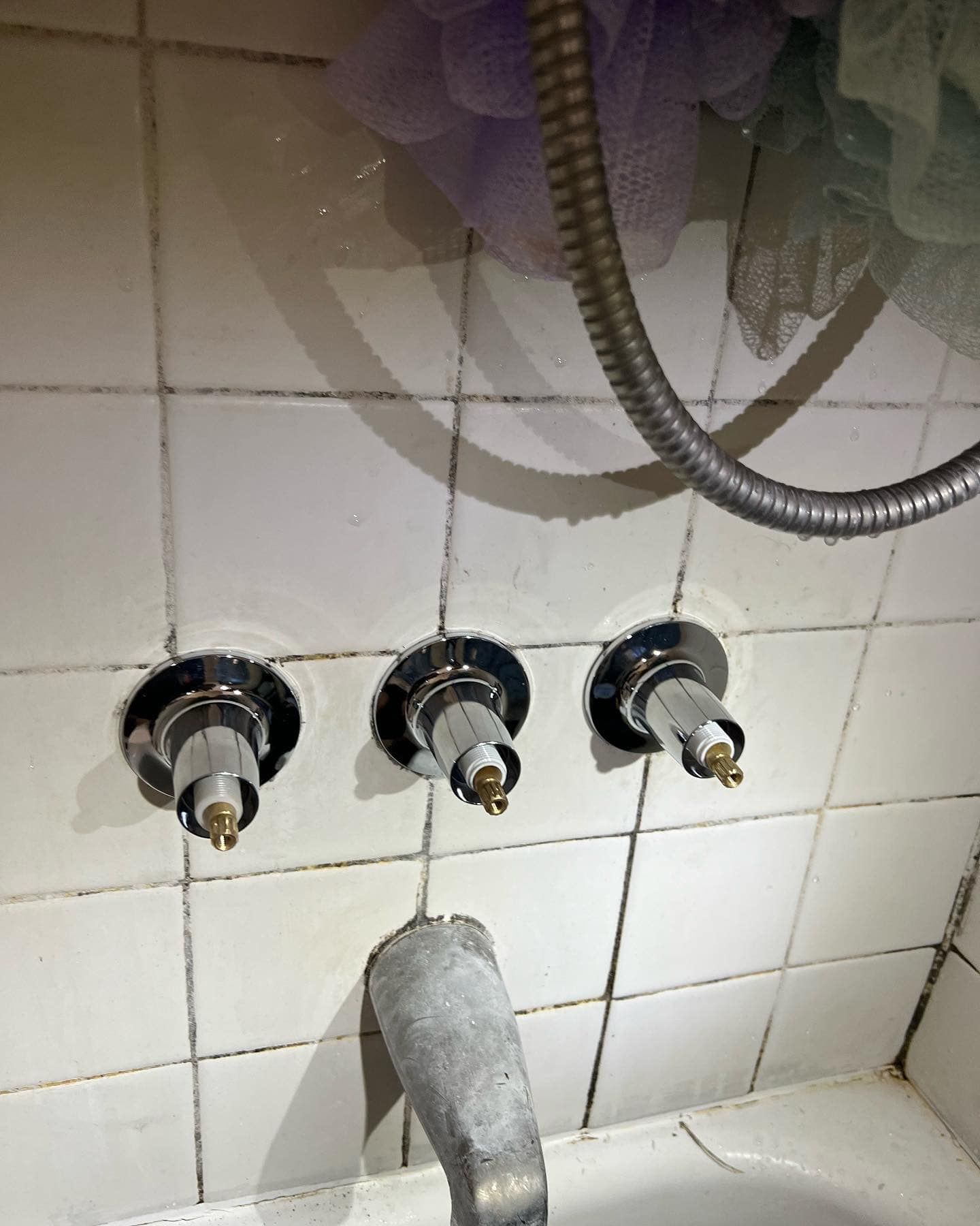 A bathroom with three faucets and a shower head