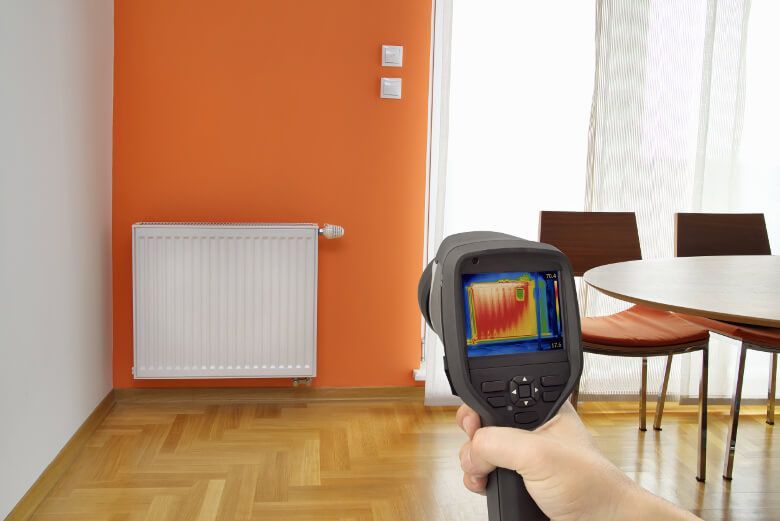 A person is holding a thermal camera in a dining room.