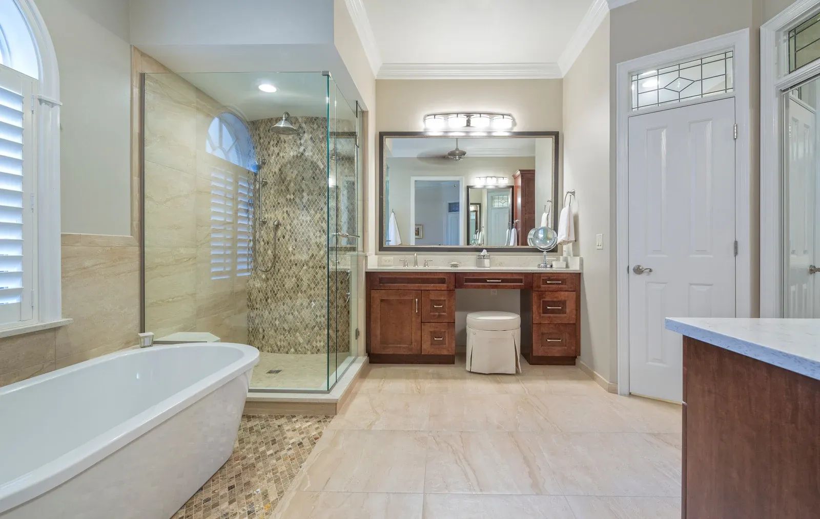 Bathroom with a soaking tub, glass shower, vanity with a large mirror, and a closed door.