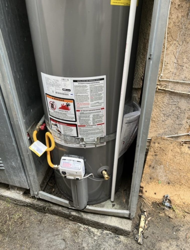 A gray water heater is sitting inside of a metal cabinet.