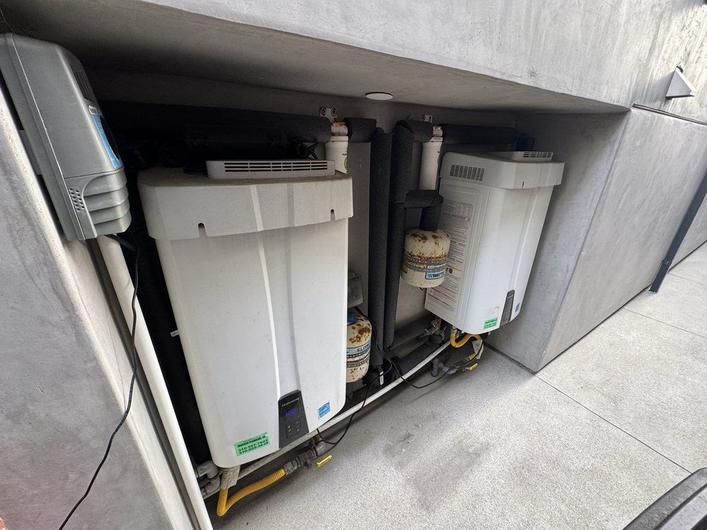 Two white tanks are sitting under a concrete wall.