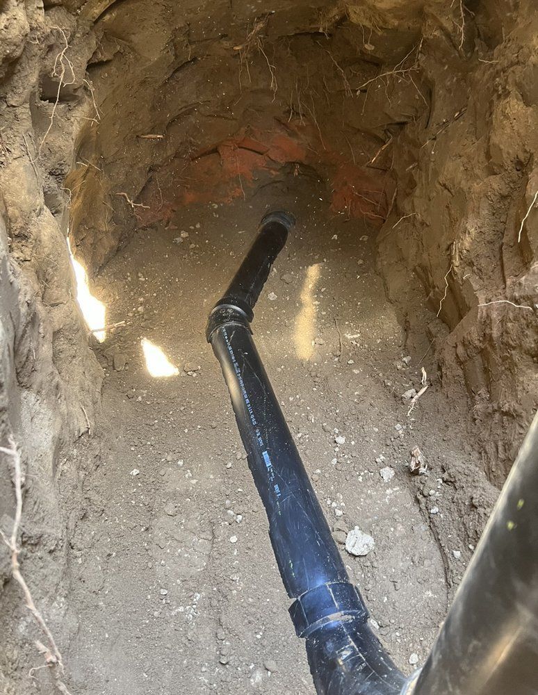 A black pipe is coming out of a hole in the ground.