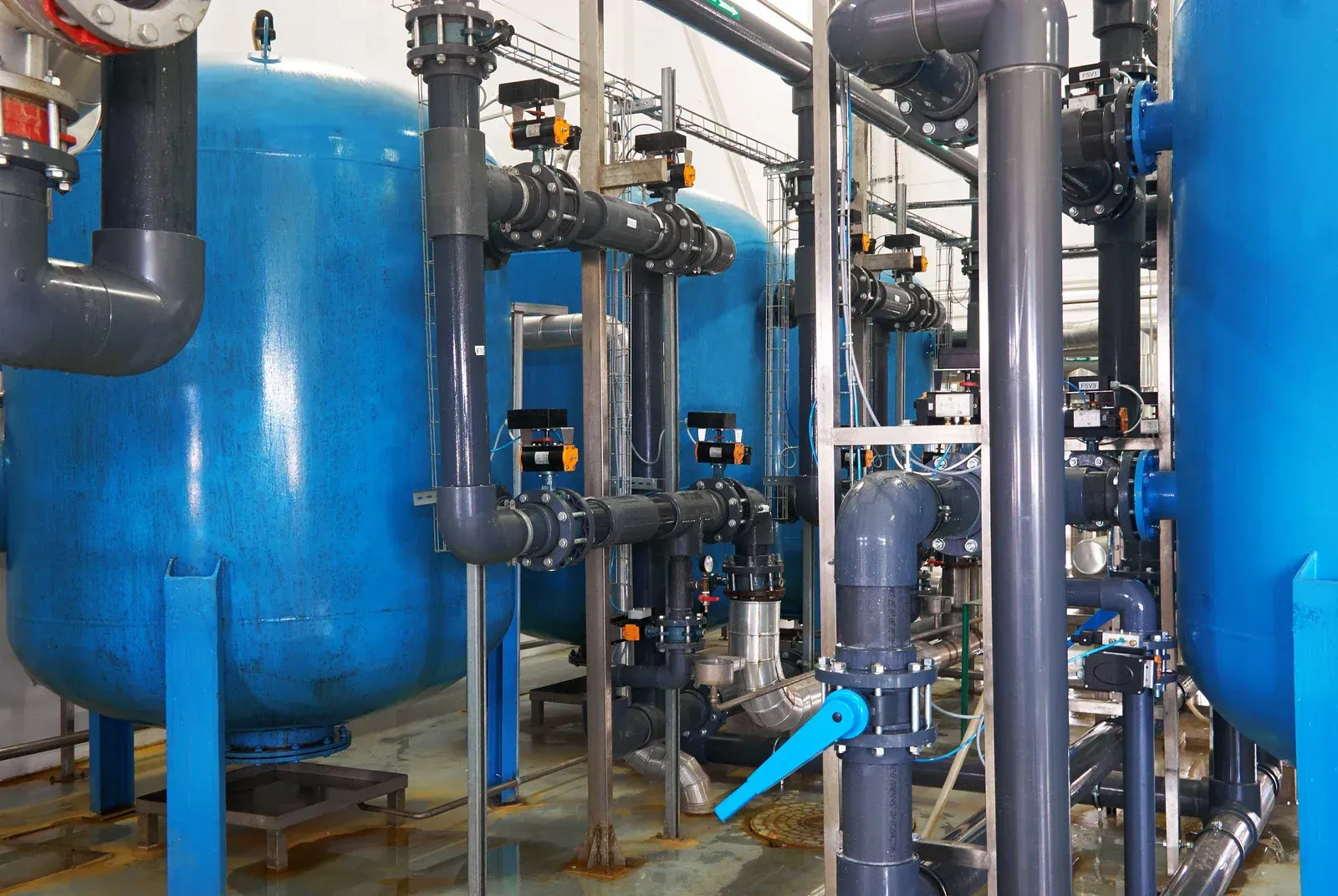 A row of blue tanks and pipes in a factory.