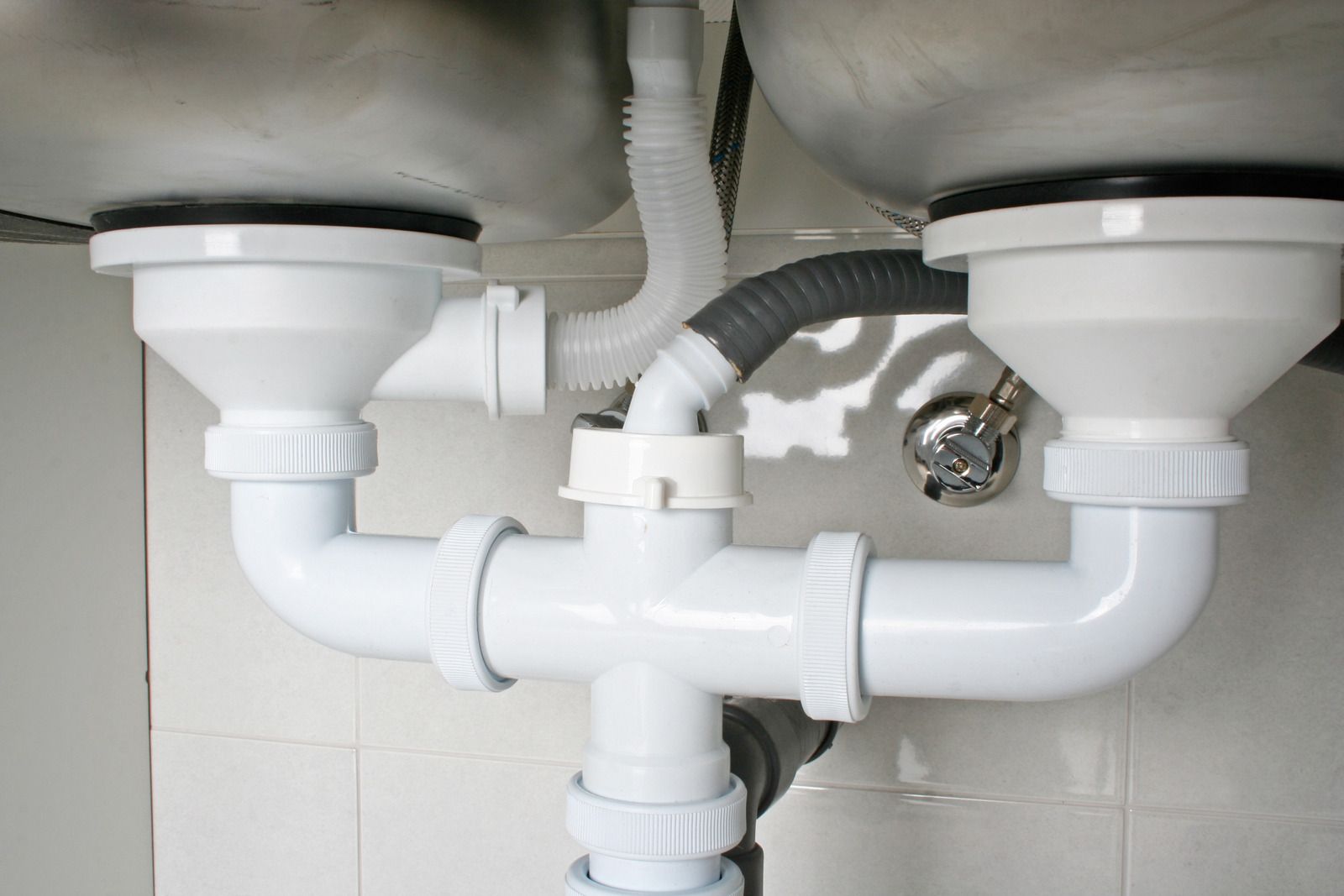 A close up of a sink with a lot of pipes underneath it.