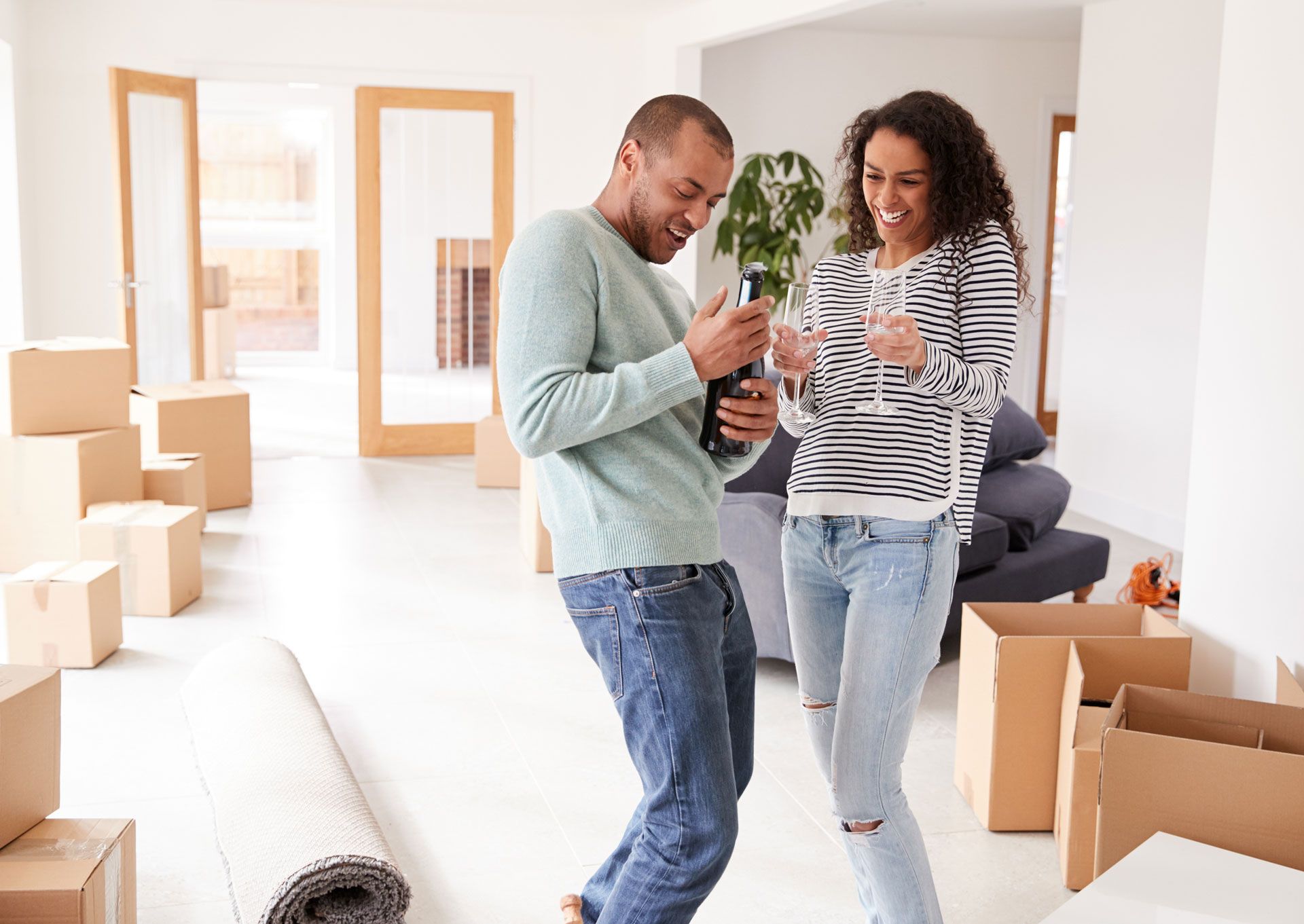 Couple celebrates in a new home, surrounded by moving boxes.