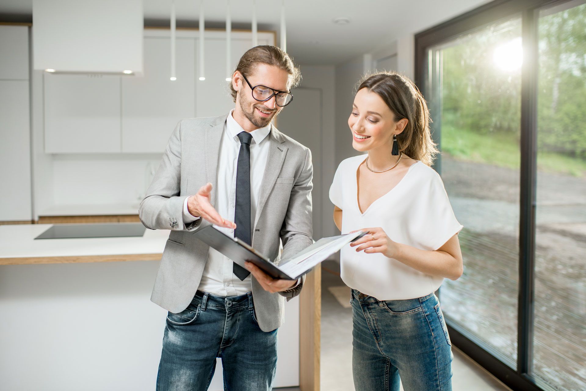 Real estate agent showing paperwork to a client in a modern home with bright natural light.