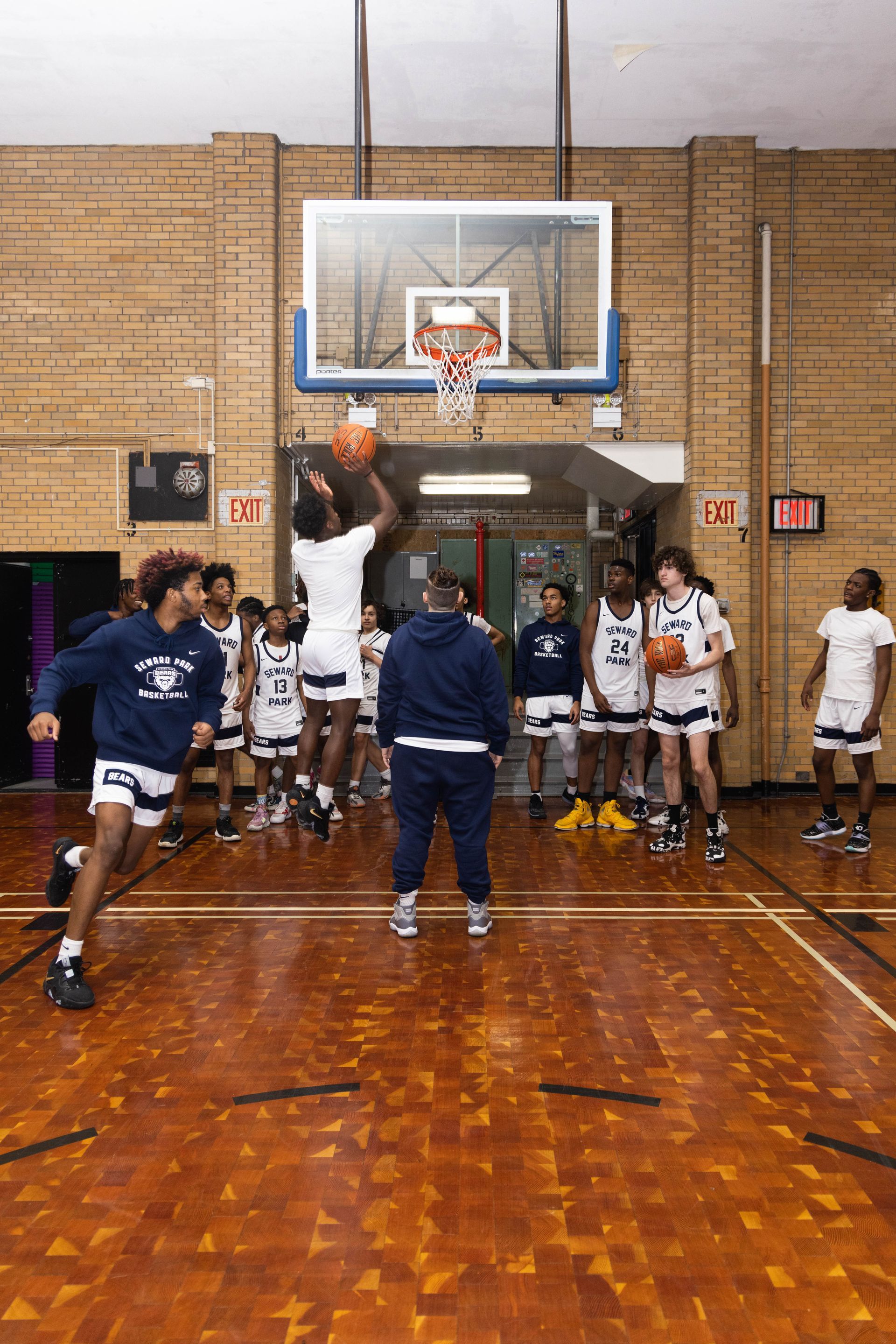 Basketball coach watching student players run drills