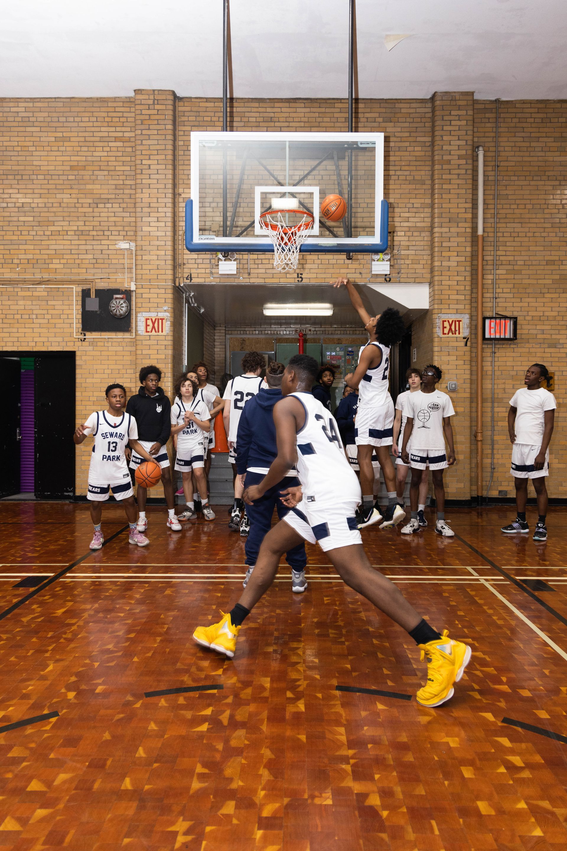 Basketball coach watching student players run drills