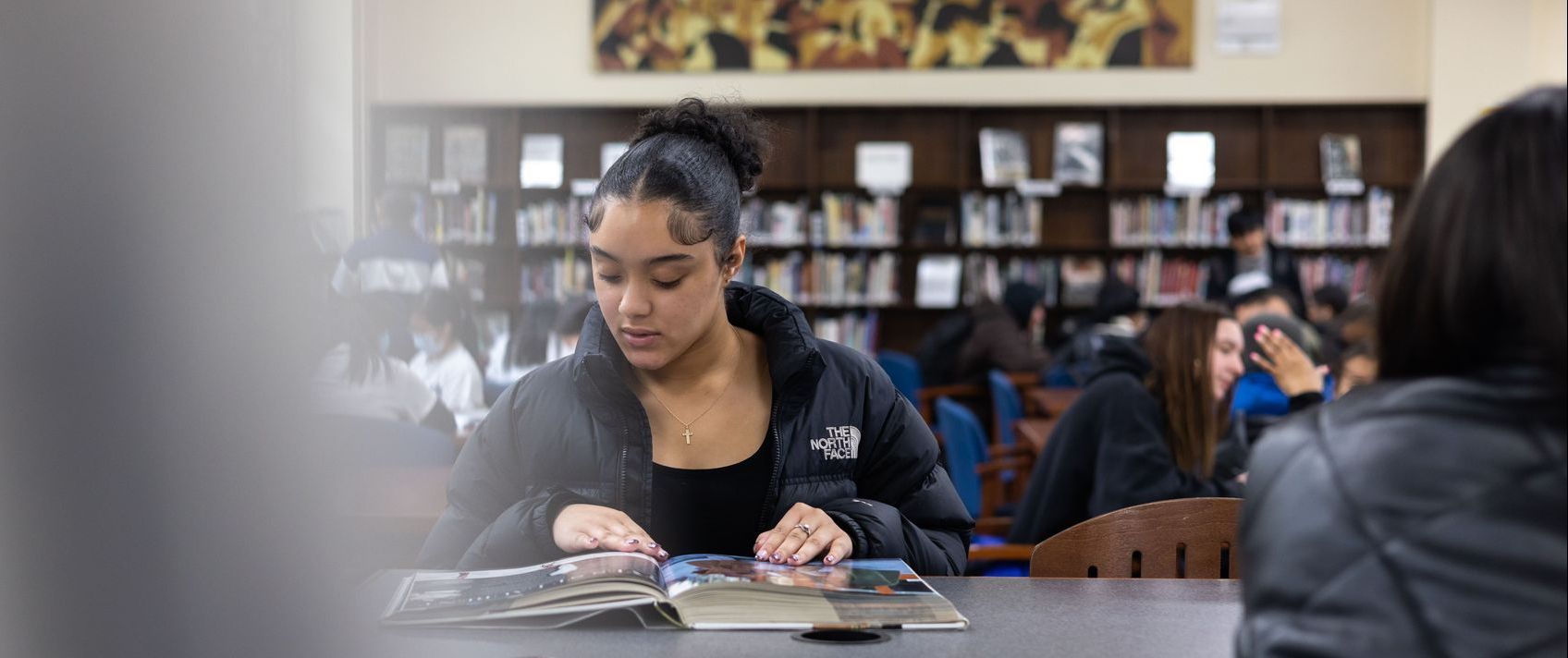 Student leafing through pages of a book in the Seward Park Campus Library