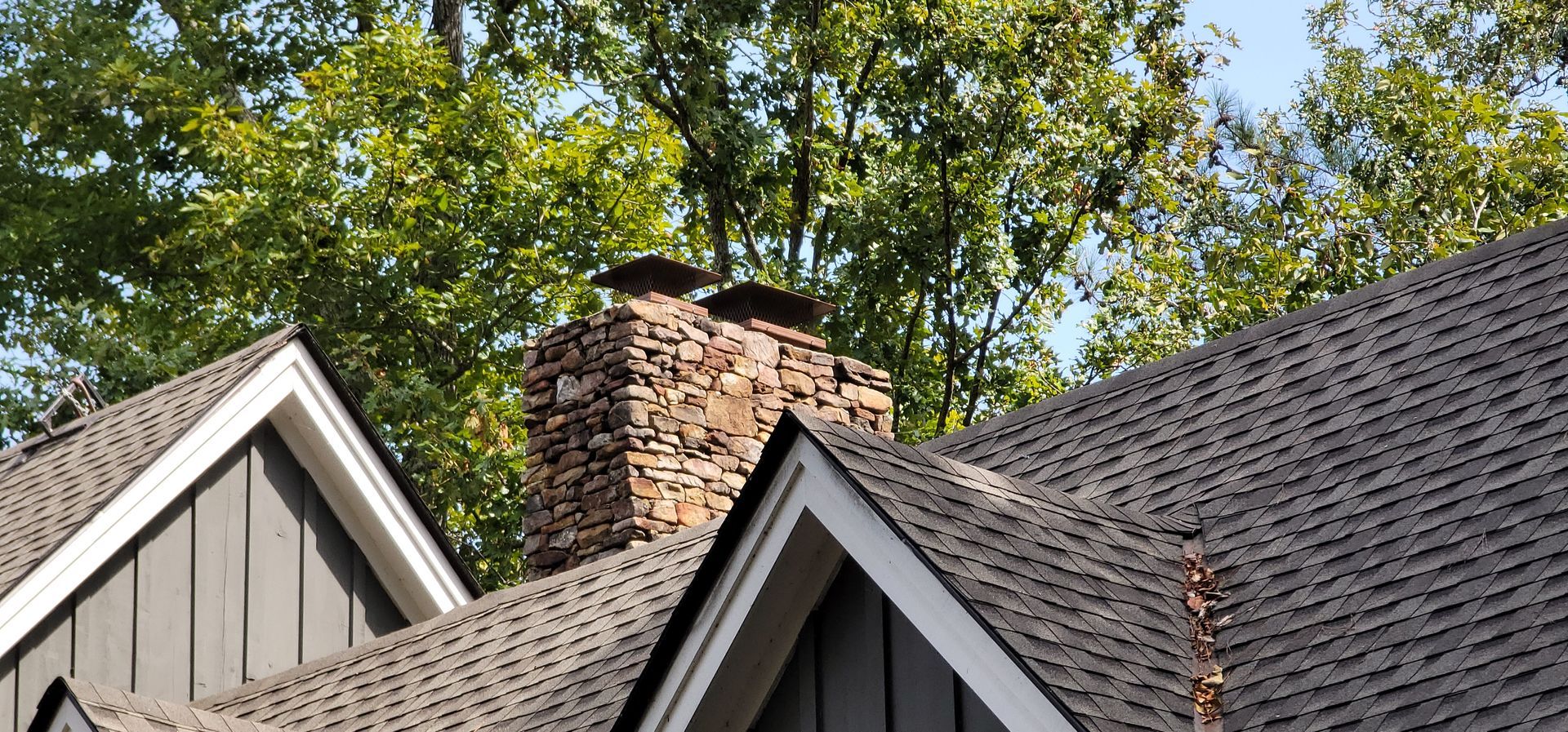 A house with a chimney on the roof and trees in the background