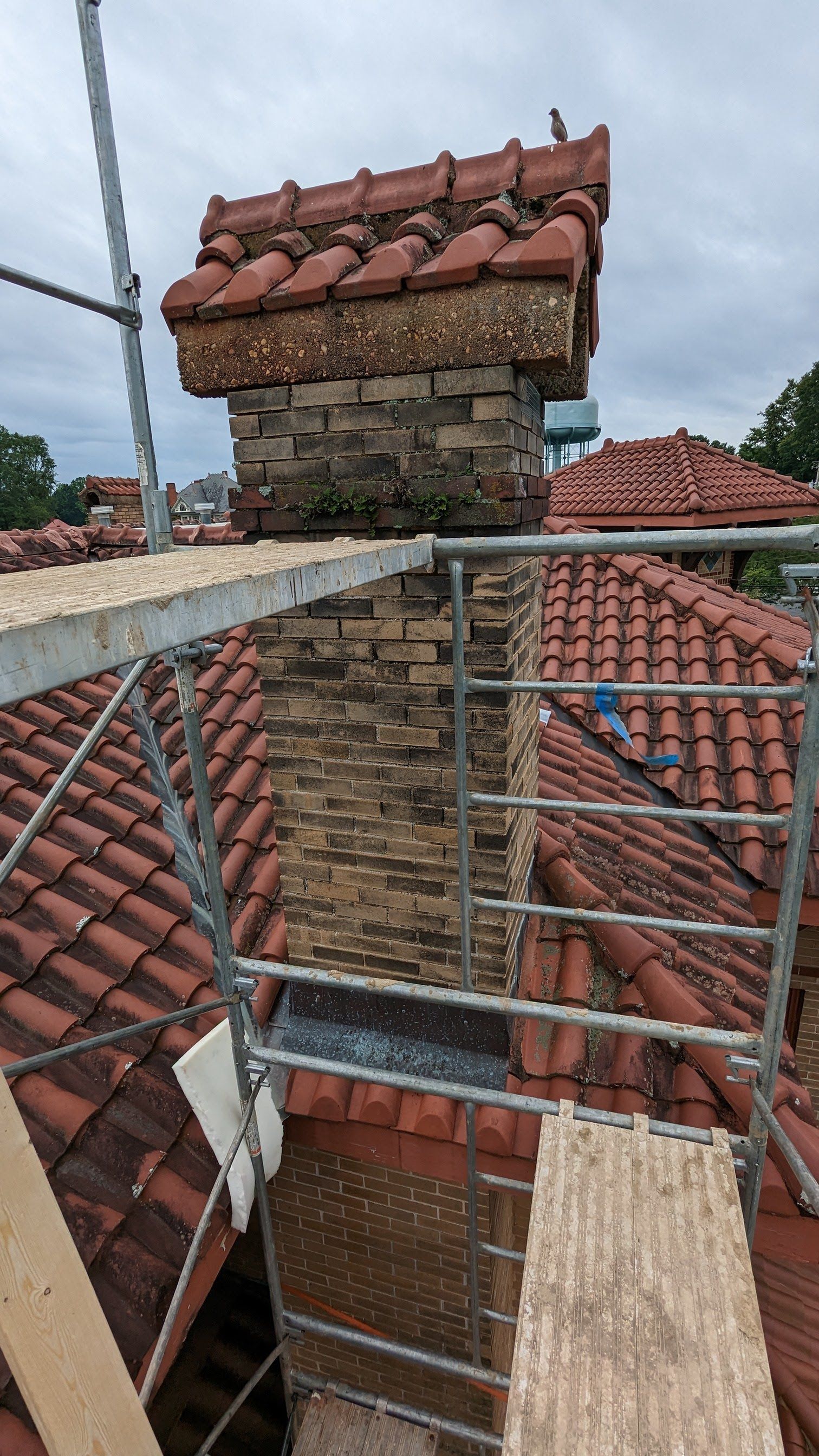 A chimney is sitting on top of a scaffolding on the roof of a building.