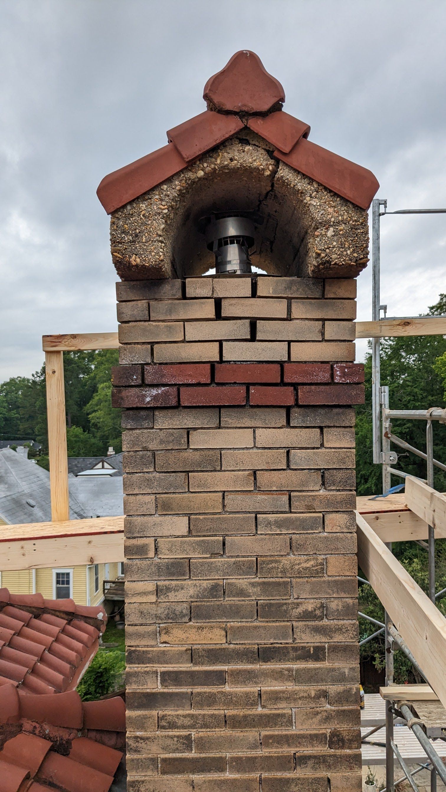 A brick chimney is being built on top of a roof.