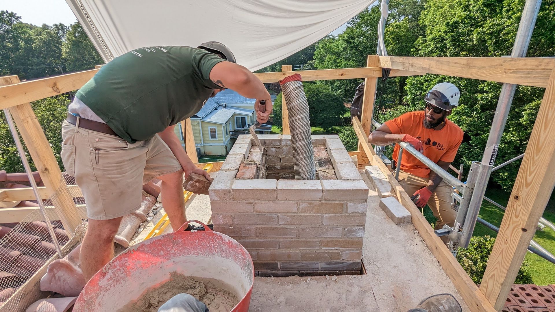 A man is pouring cement into a hole in a brick wall.