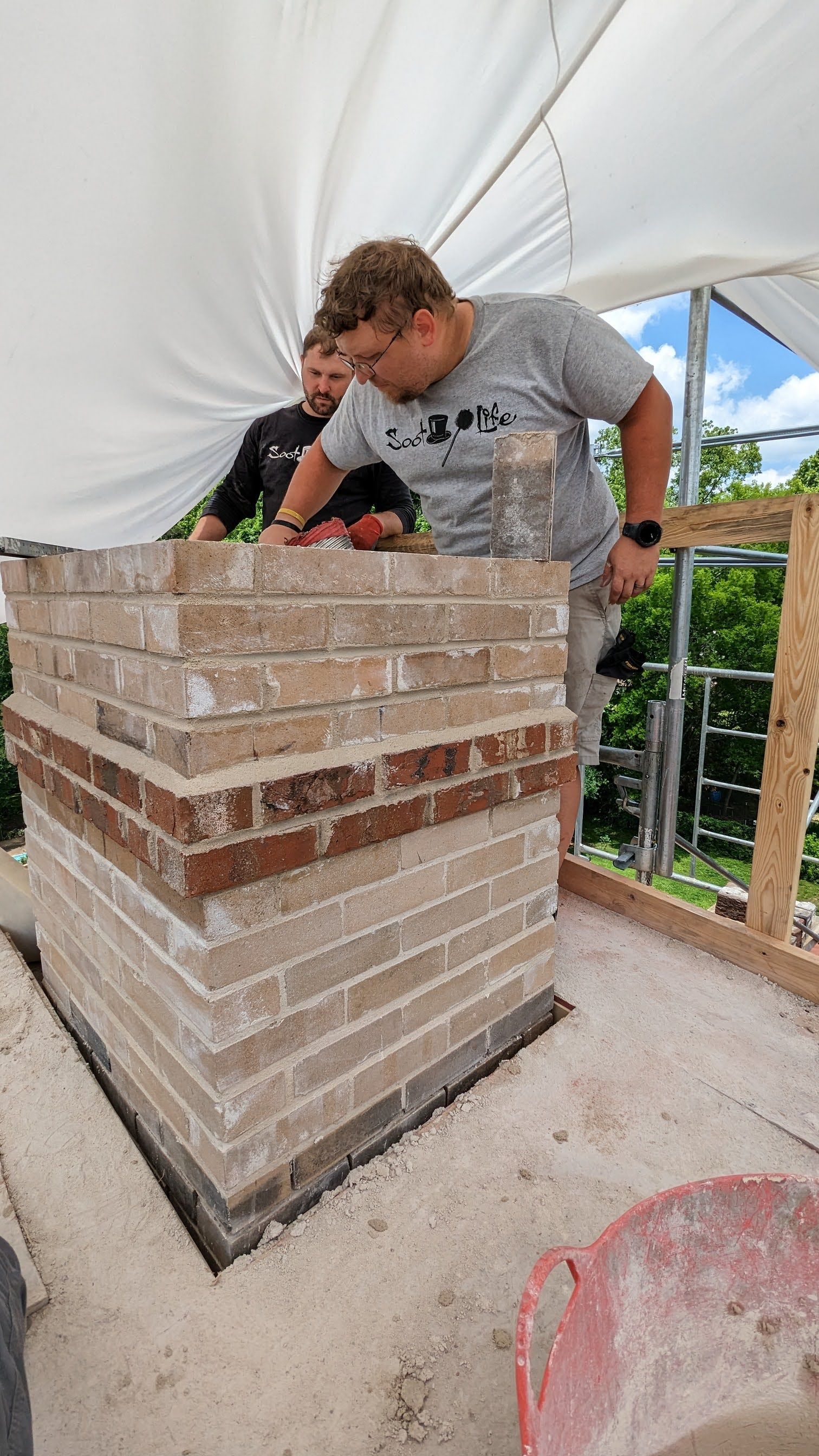 A man is laying bricks on top of a brick wall.