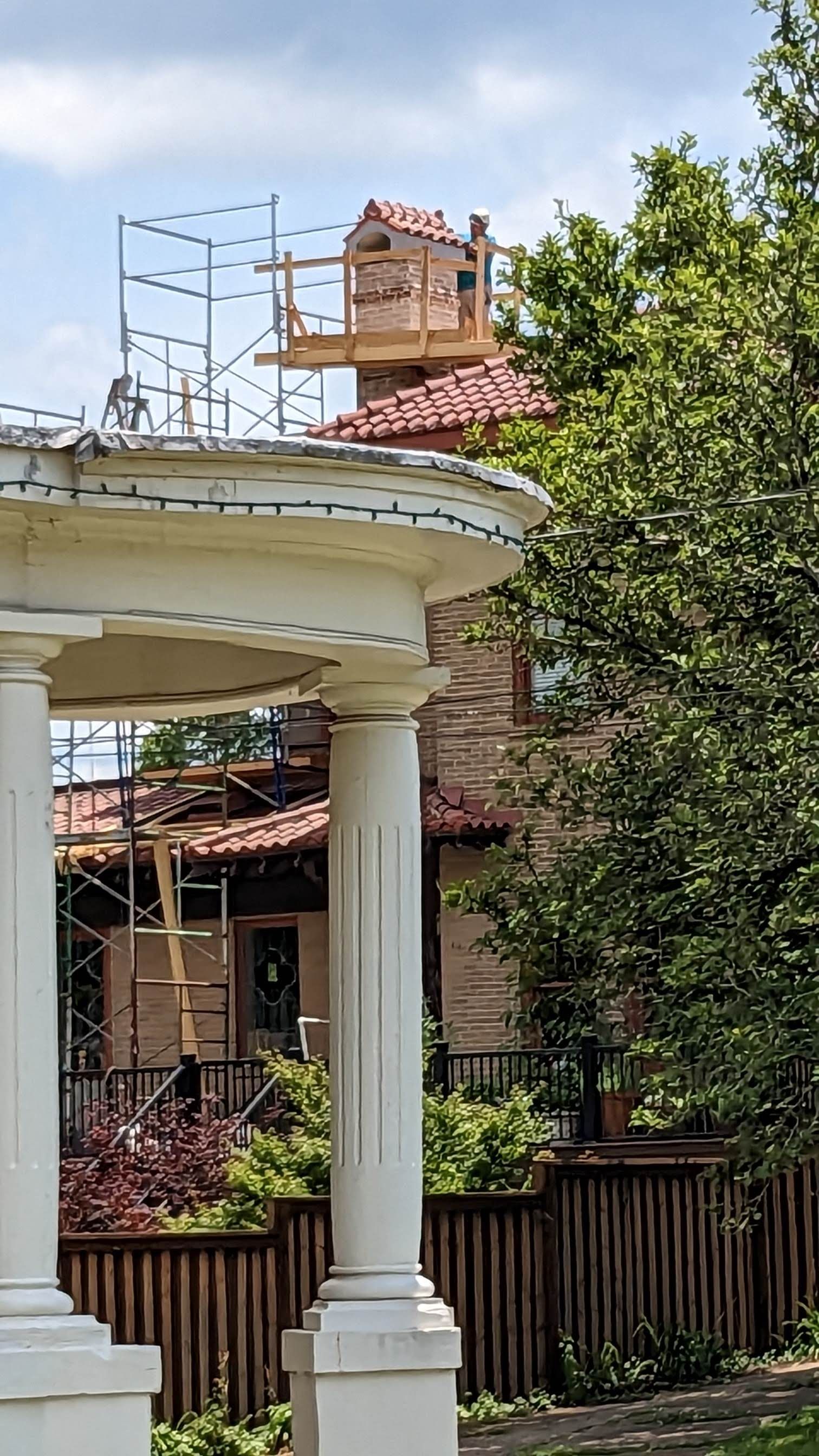 A gazebo with scaffolding on top of it in front of a house under construction.