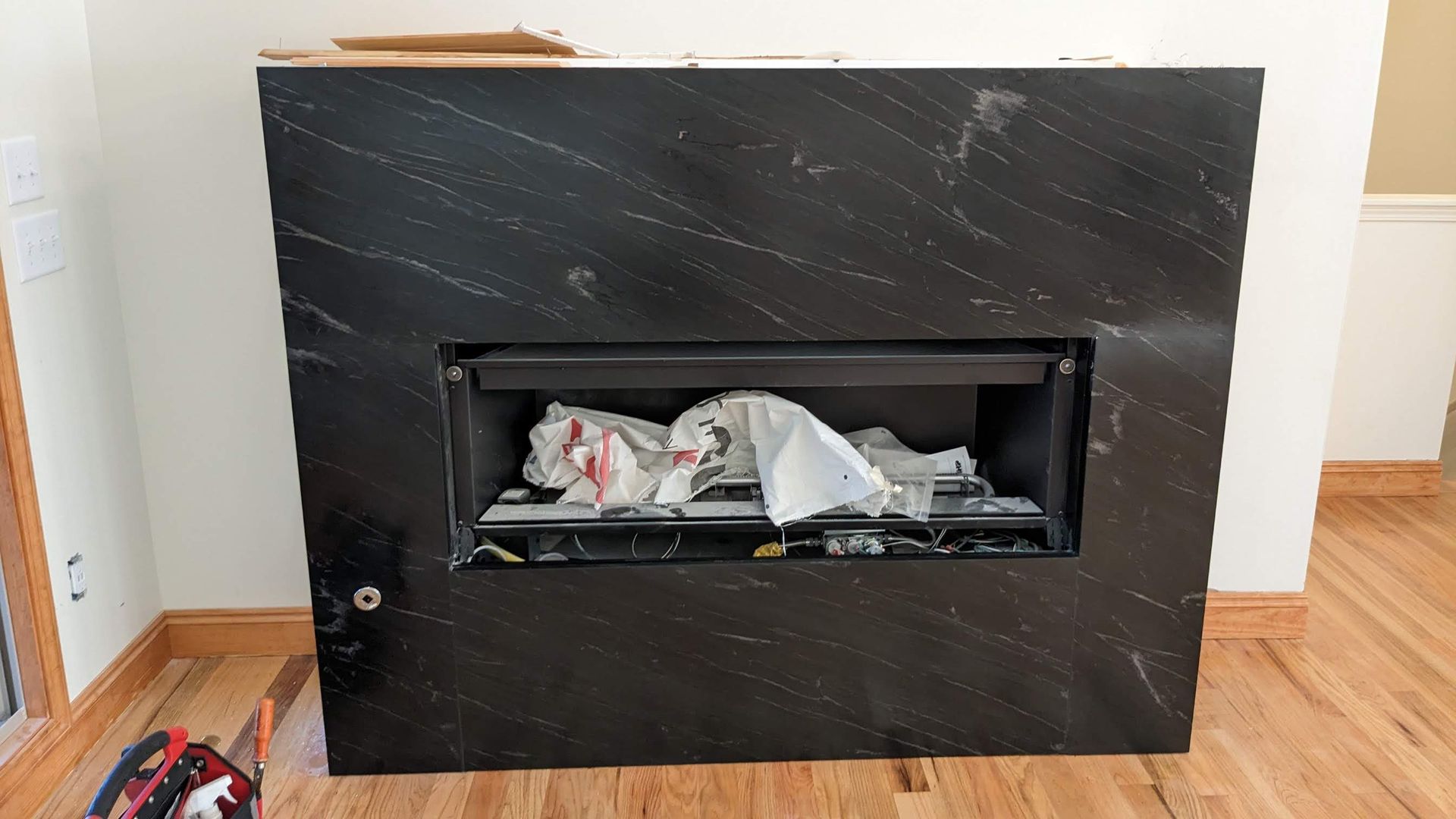 A black fireplace is sitting on a wooden floor in a living room.