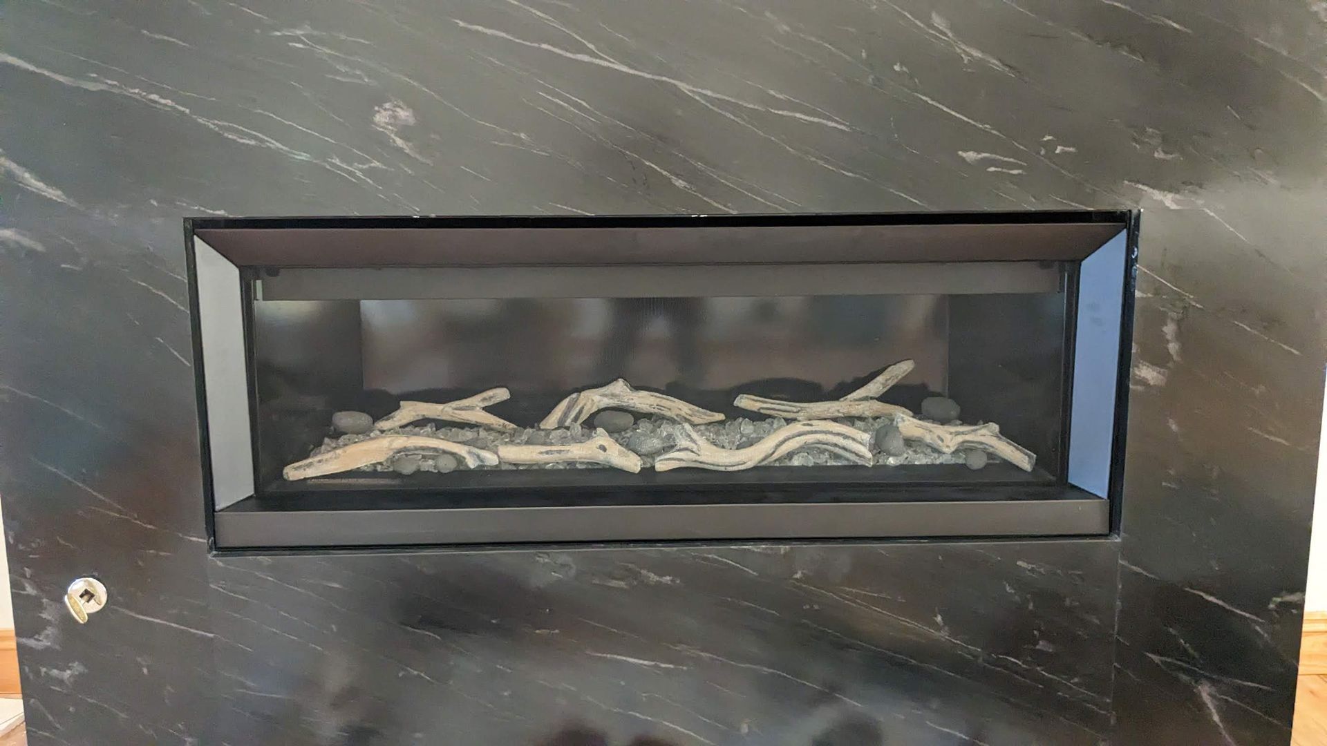 A black fireplace with a glass door is sitting on a wooden table.