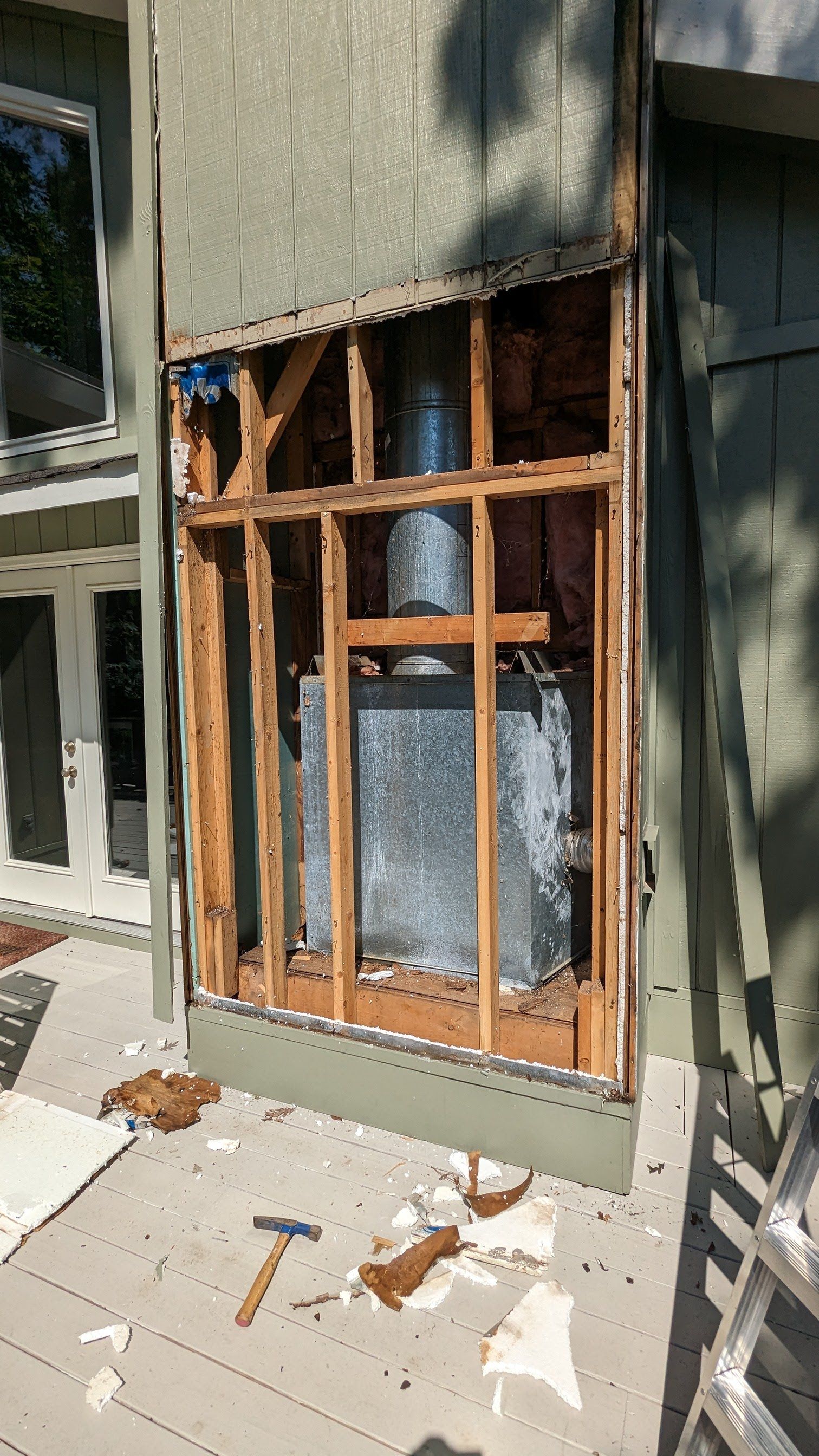 A fireplace is being removed from the side of a house.