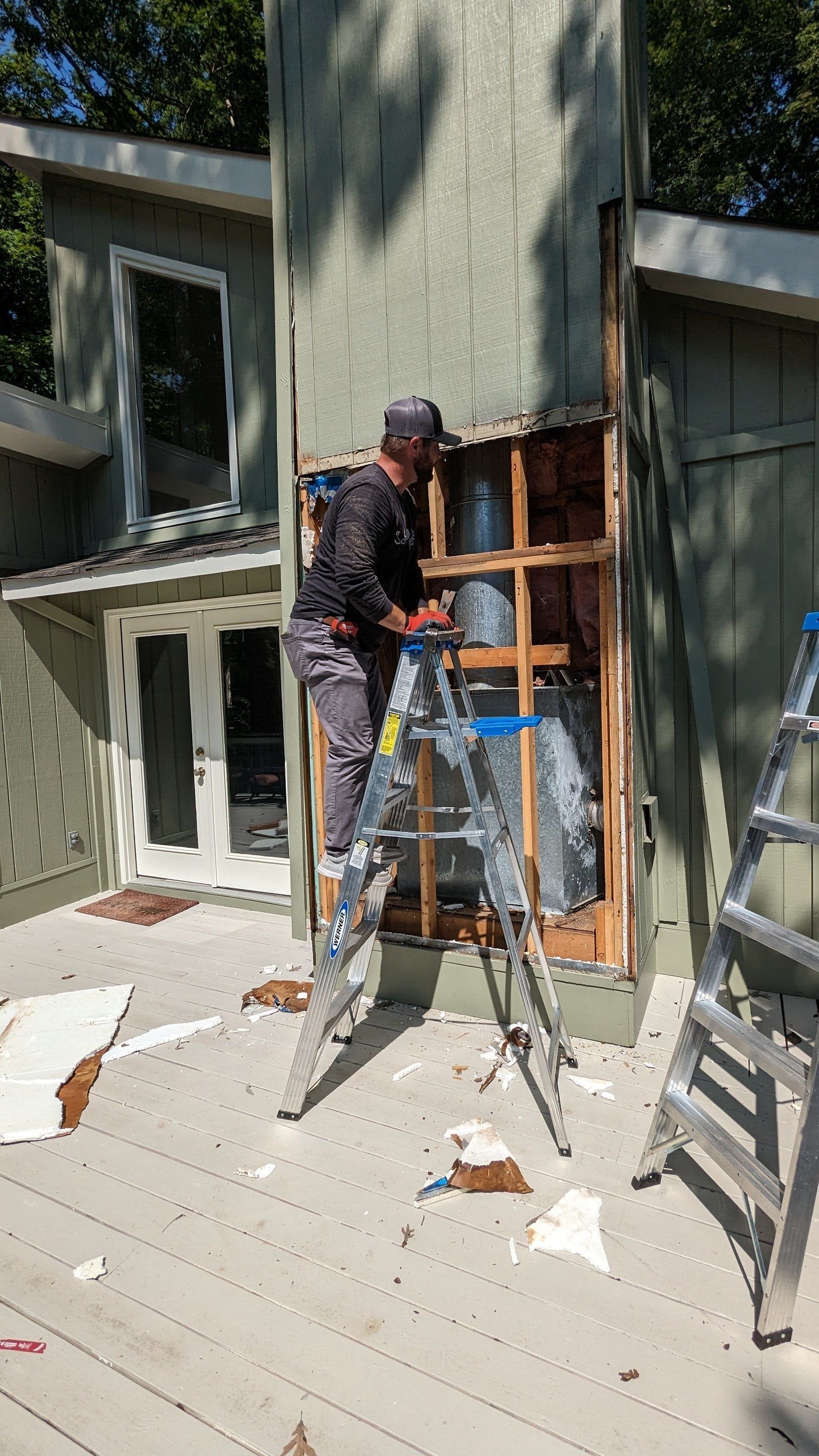 A man is standing on a ladder in front of a house.