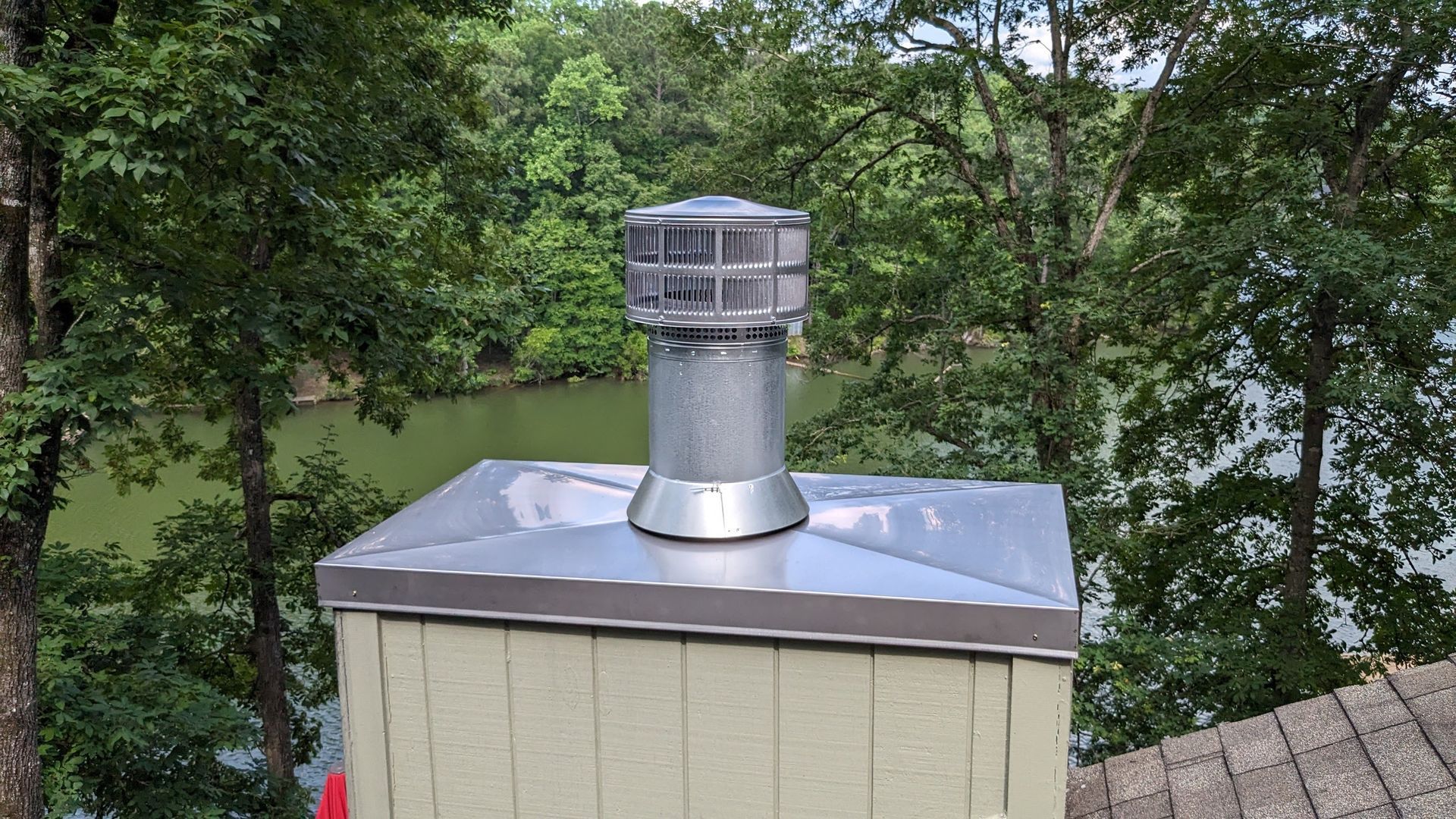 A chimney is sitting on top of a wooden building next to a body of water.
