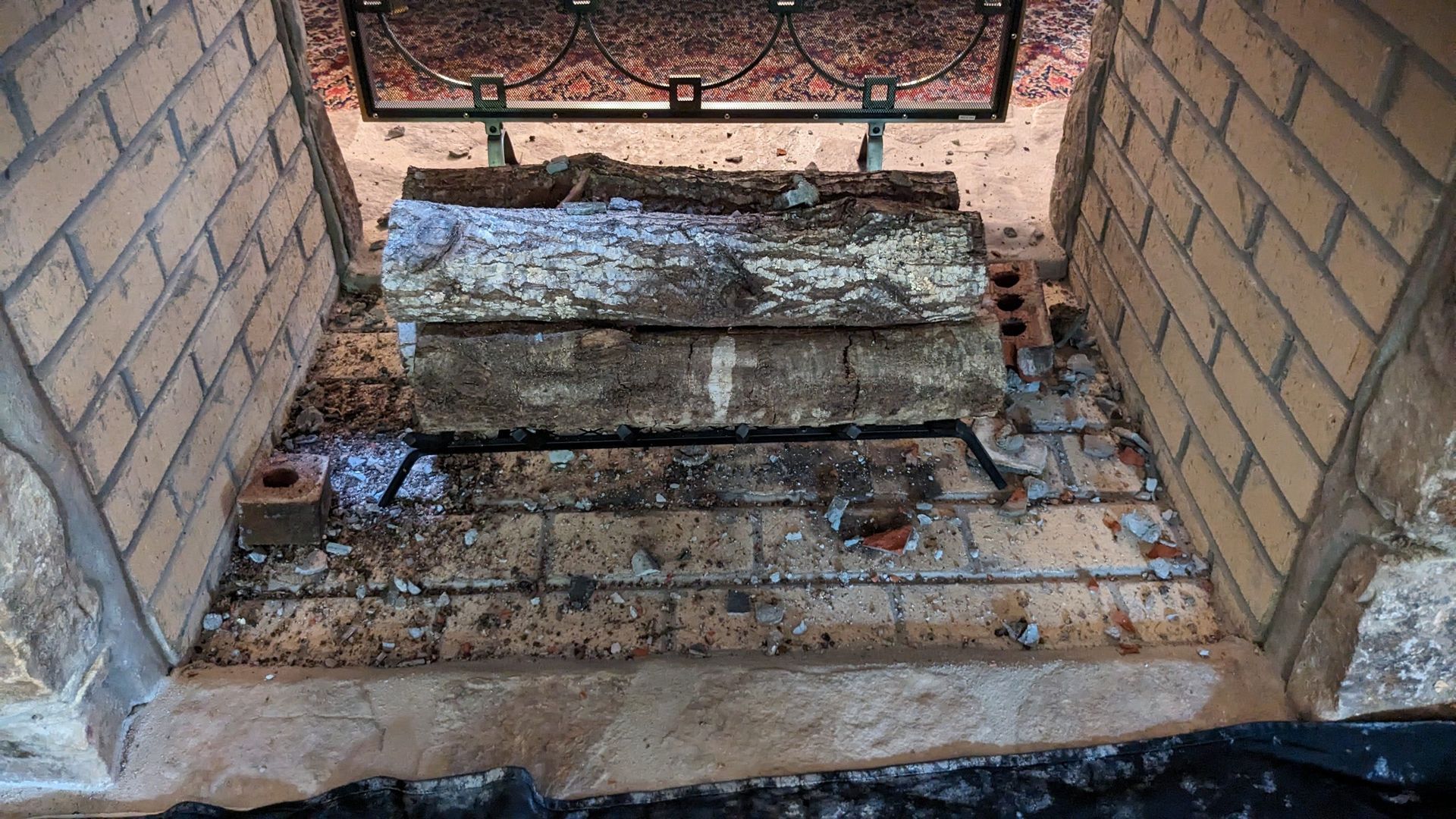 A brick fireplace with a stack of logs in it.