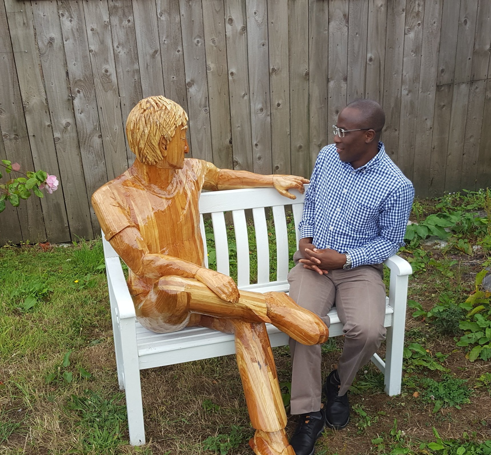 Life size wooden man sitting with a human man