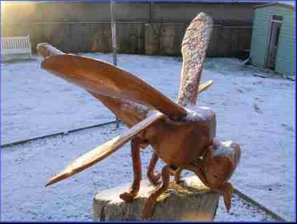 A wooden sculpture of a Dragonfly in winter with iced wings. made by Robert, Ingrained Culture