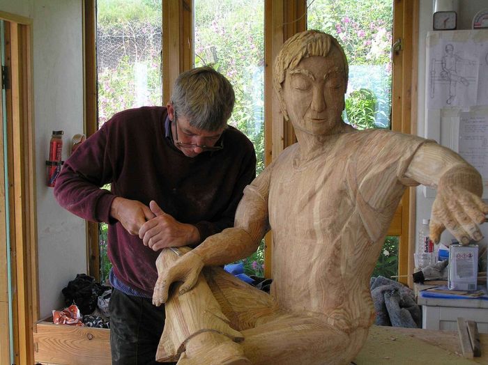 An image of Robert from Ingrained Culture sculpting a life size wooden figure.