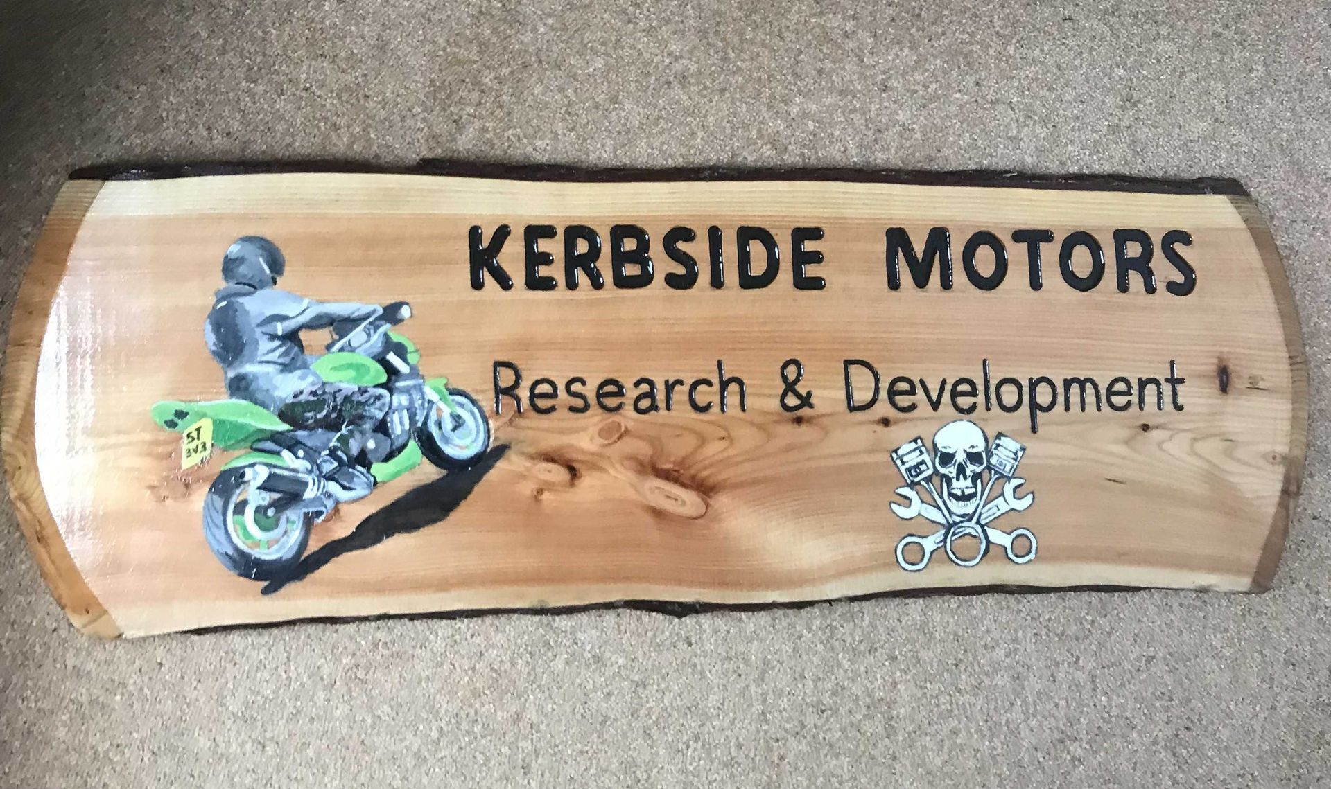 A wooden business sign for a mechanic with  a full colour illustration of a motorbike. 