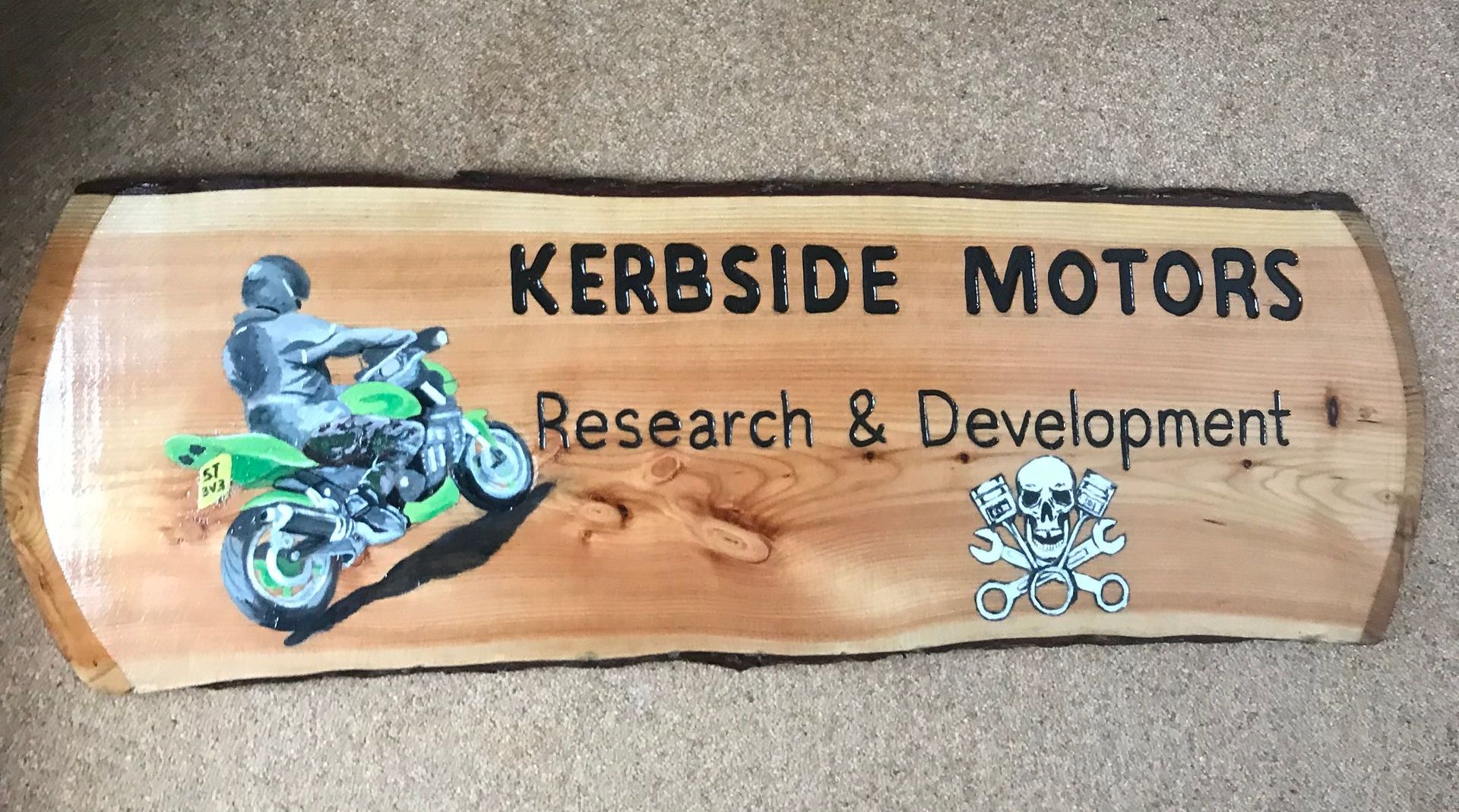 A wooden business sign for a mechanic with  a full colour illustration of a motorbike. 