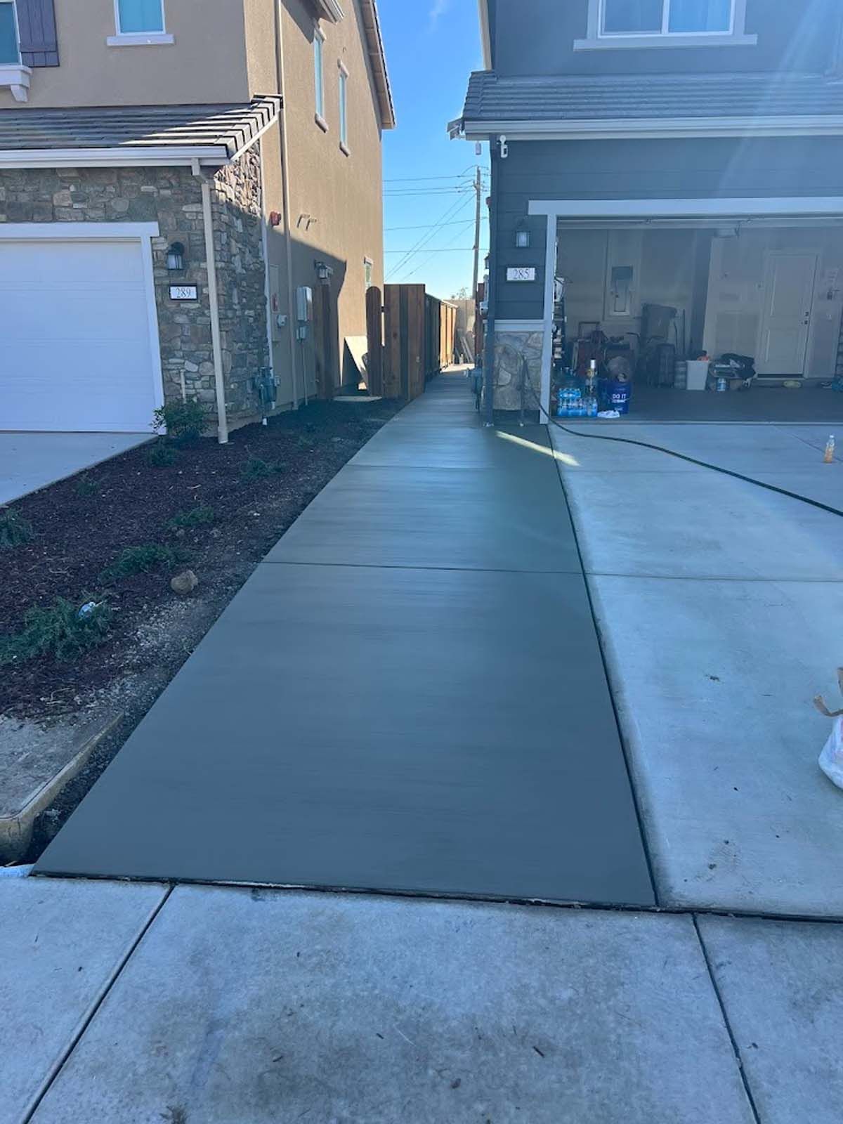 Newly poured concrete walkway between two houses.