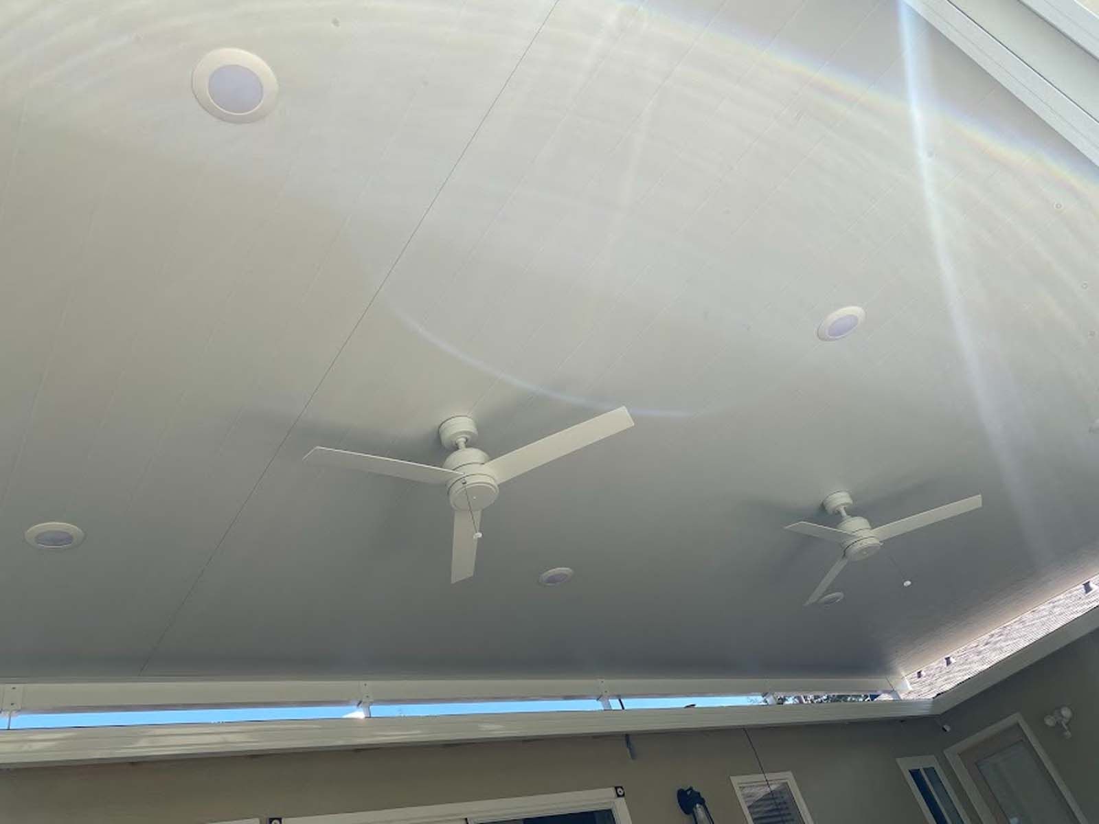 White ceiling with two fans and recessed lights.