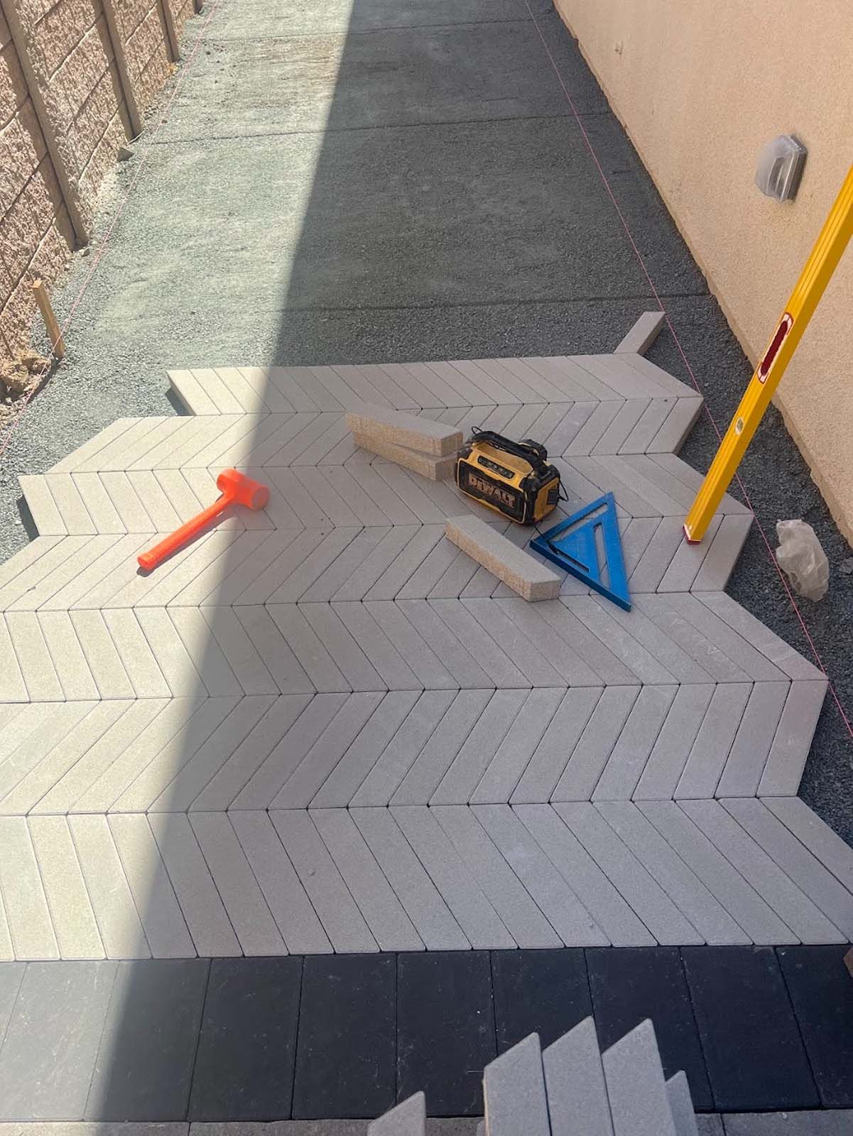 Herringbone brick paving installation in progress with tools.