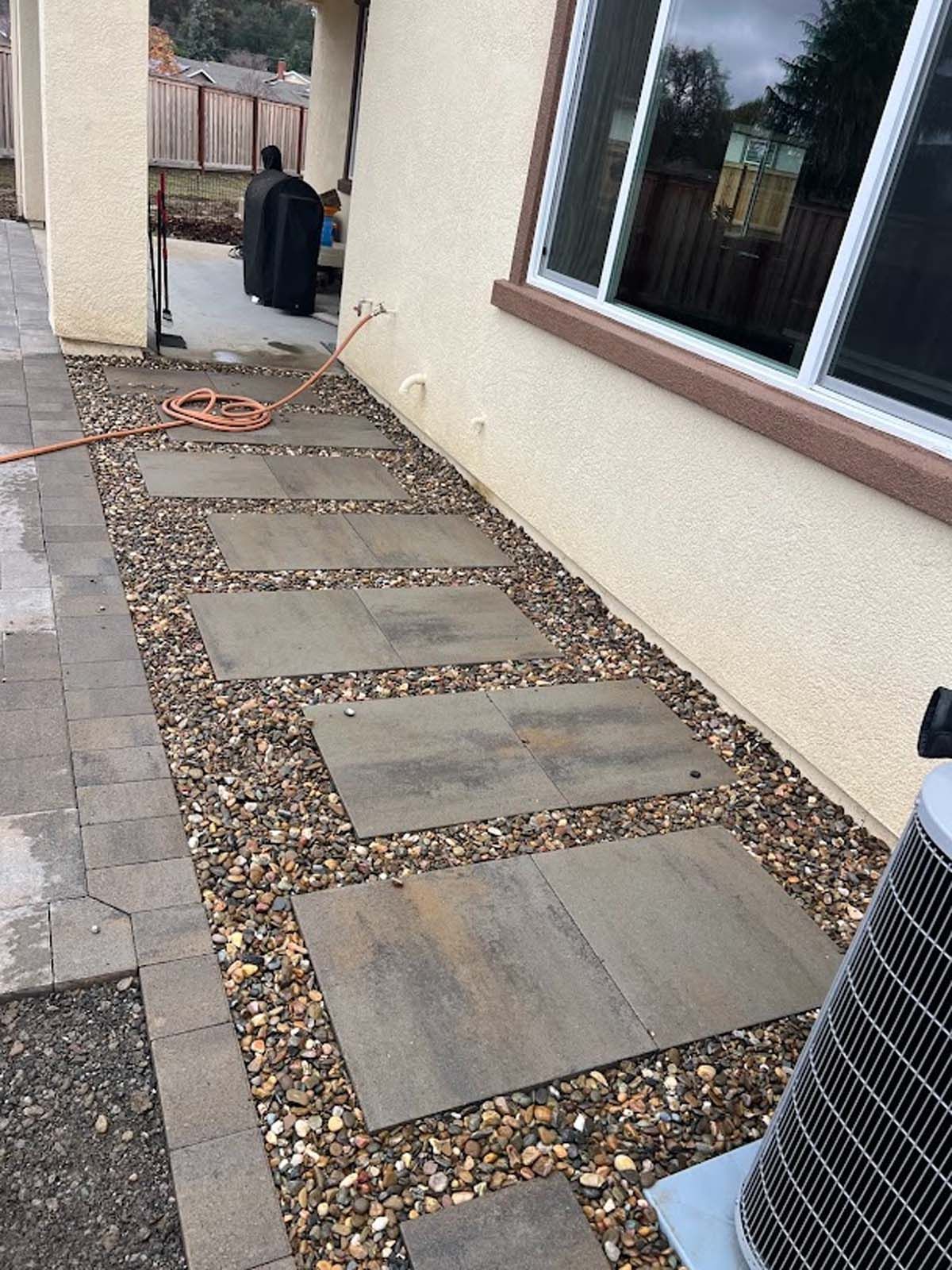 Stone pathway with stepping stones bordered by gravel next to a house.