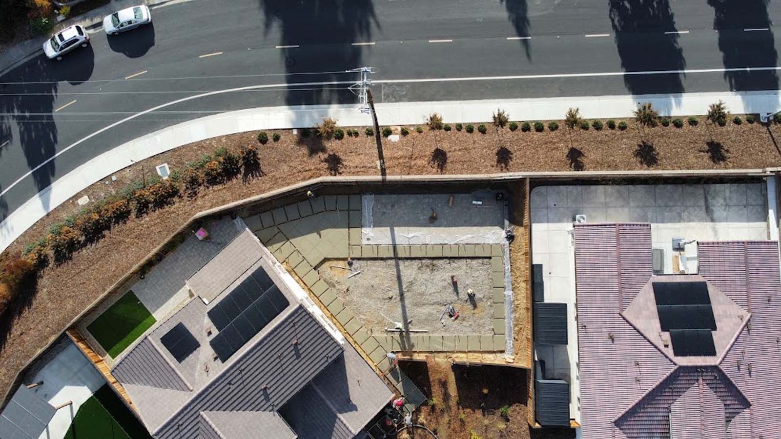 Aerial view of houses with solar panels, road, and a car.