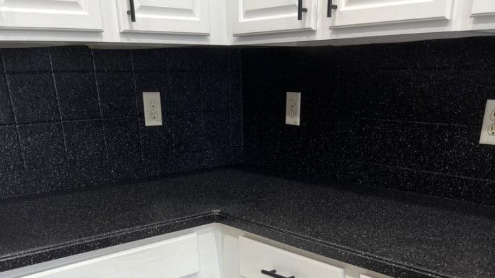 a kitchen with black counter tops and white cabinets .