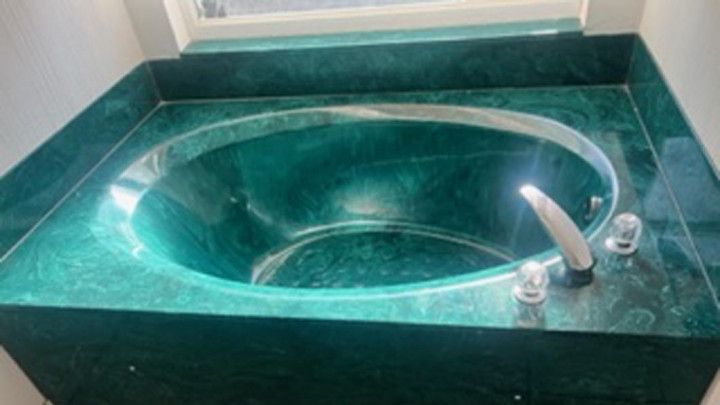 a green bathtub is sitting on top of a green counter in a bathroom .