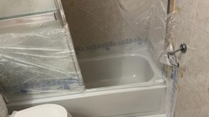 a bathroom with a toilet , tub and shower covered in plastic .