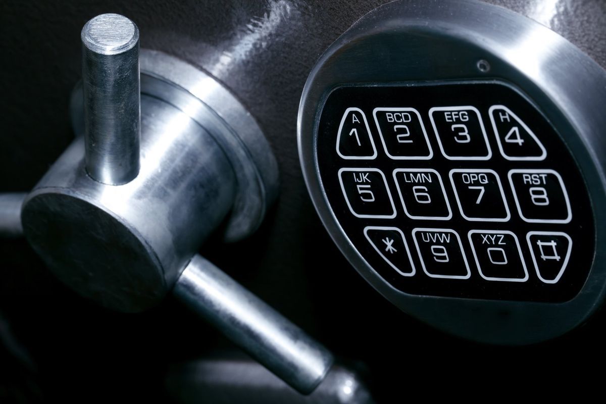 Close-up of a silver safe's dial and handle. The dial has a keypad with numbered buttons.