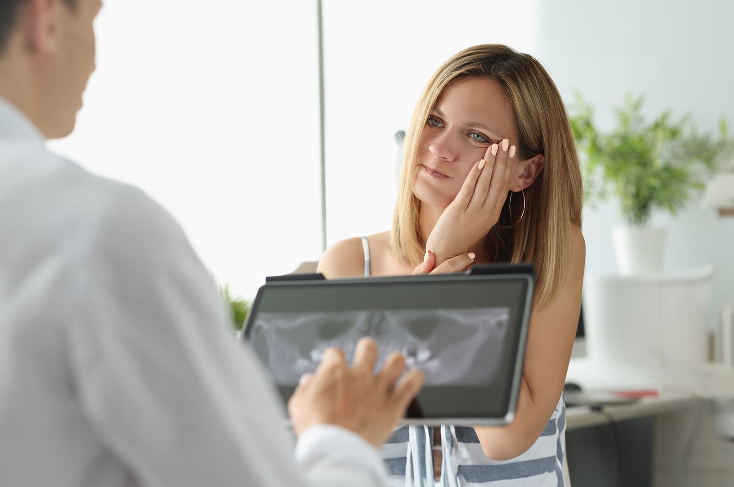 A patient with a toothache at a wisdom teeth removal surgeon appointment, with an X-ray image.