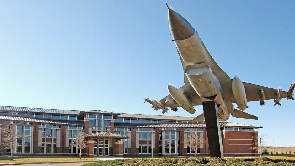 a statue of a fighter jet is in front of a building