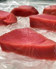sliced tuna fish placed on top of ice at a market