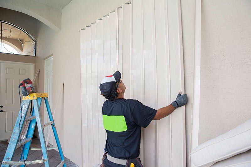 A man is standing next to a ladder while installing a door.