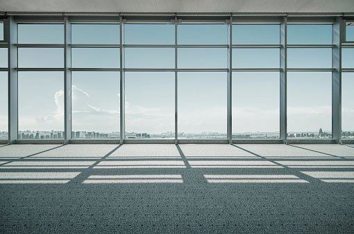 An empty room with a lot of windows and a view of the city.