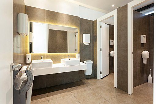 A bathroom with two sinks , a mirror , and a trash can.