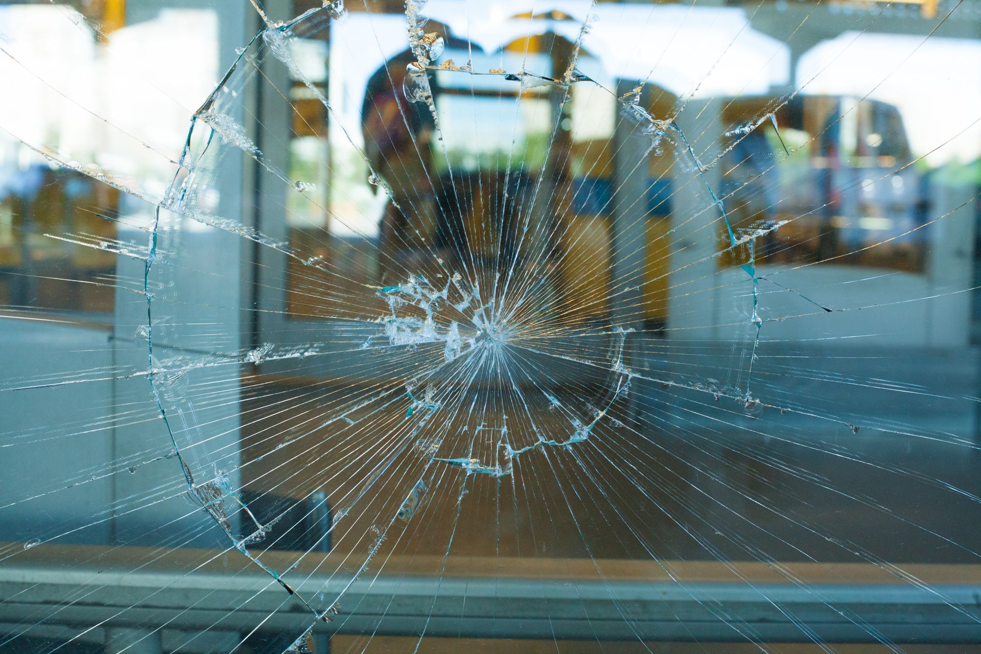 Impact-shattered storefront window needing professional glass repair service for safety.