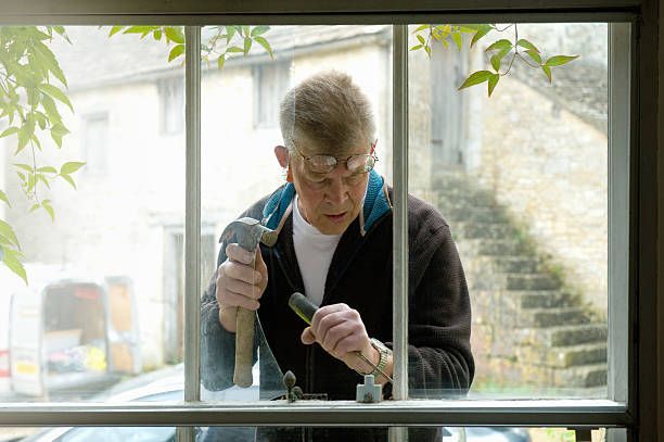 Expert glazier fixing broken window glass with precision and care.