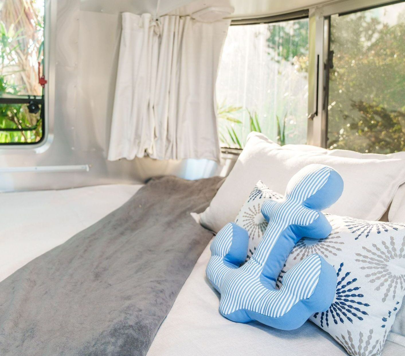 A bedroom with a bed , curtains and a light hanging from the ceiling.