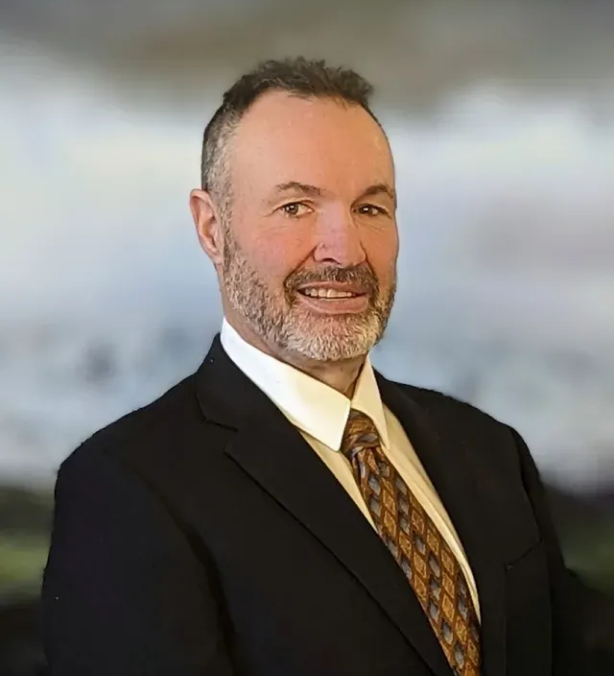 A man in a suit and tie is smiling for the camera.